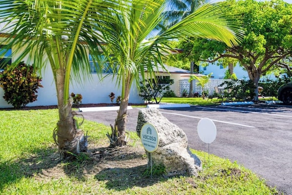 A residential property with a well-maintained lawn, palm trees, and a house with a visible garage door. - Coconut Grove Singer Island - Units 1, 3, & 4 (West Palm Beach)