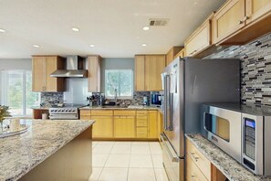 Eine moderne Küche mit Holzschränken, Edelstahlgeräten und einer Arbeitsplatte aus Granit.