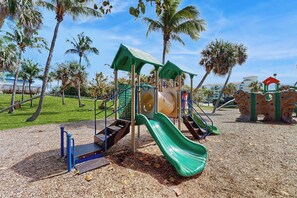 A playground with slides and climbing structures, surrounded by palm trees and a clear sky. - Azure Haven - Private Pool (Lantana)