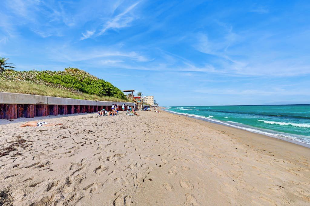 A sandy beach with footprints, a lifeguard tower, and a building in the background.