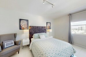 Ein Hotelzimmer mit einem Bett, einem Nachttisch, einer Lampe, einer Couch und zwei gerahmten Bildern an der Wand.