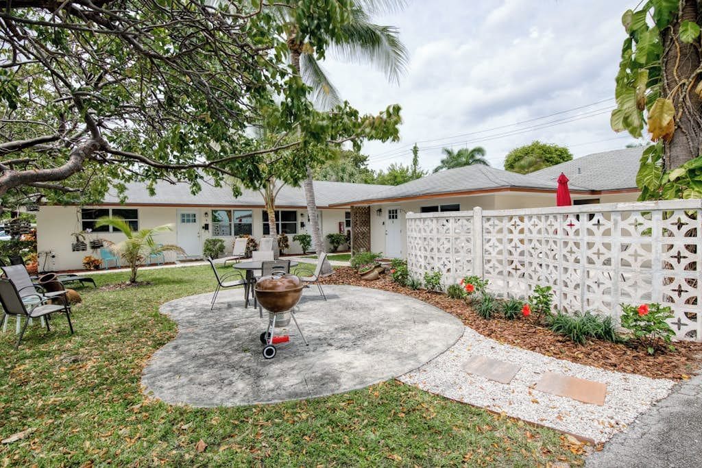 A backyard with a barbecue grill, outdoor seating, and a white fence.