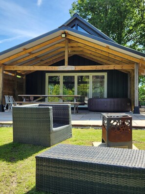 A covered outdoor seating area with wicker furniture and a metal table. - The Pigsty at the Secret Garden (Ashford)