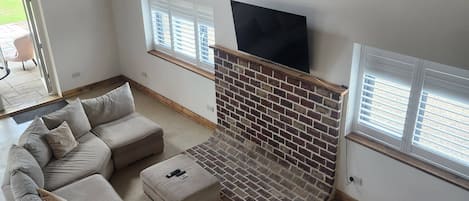 A living room with a sectional sofa, a fireplace, and a TV mounted on the wall.
