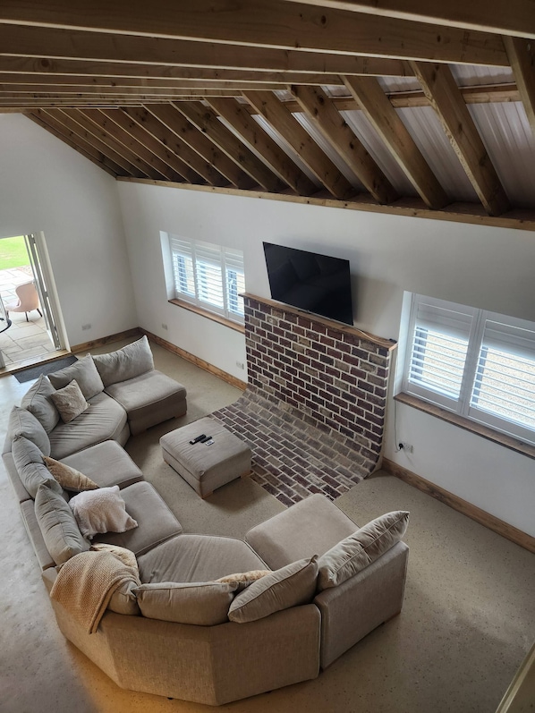 A living room with a sectional sofa, a fireplace, and a TV mounted on the wall.