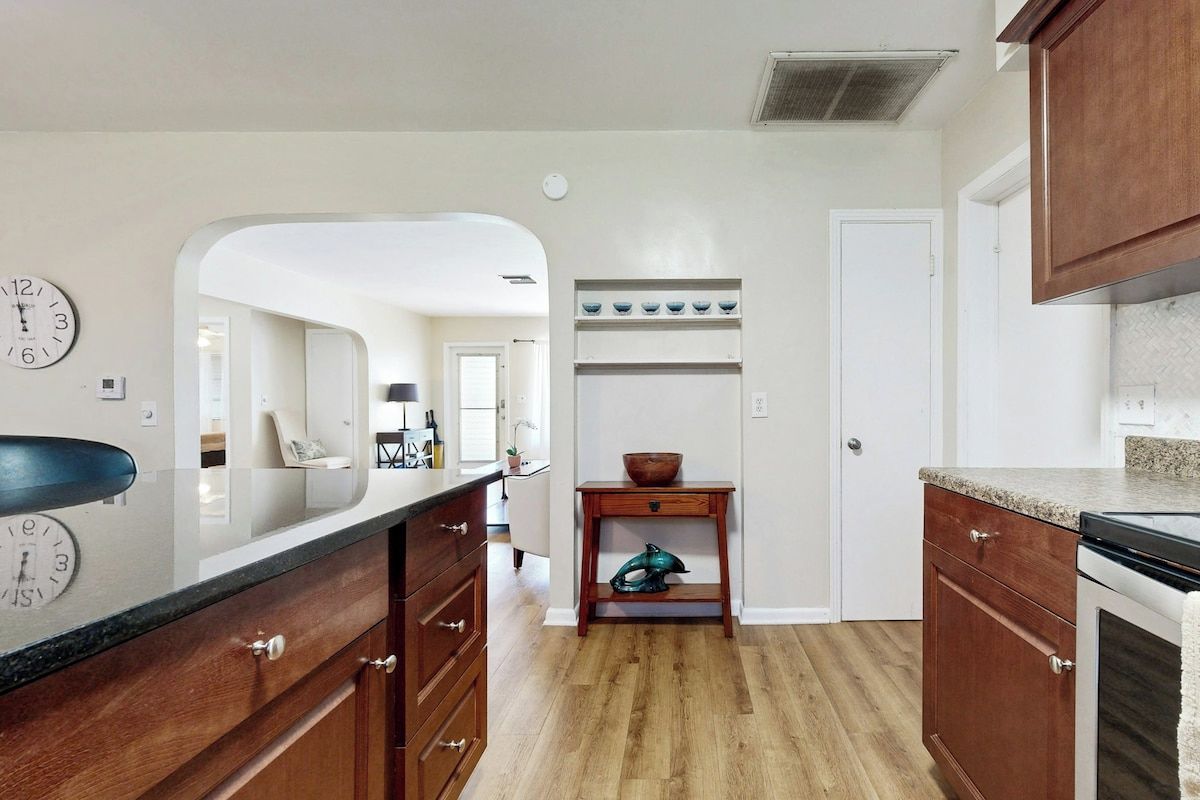 A kitchen with wooden cabinets, a countertop, a sink, and a clock on the wall.
