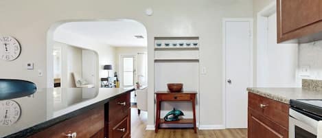 A kitchen with wooden cabinets, a countertop, a sink, and a clock on the wall.