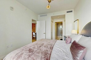 A bedroom with a bed, bedside table, lamp, and a door leading to another room. - NoMad #628 - Private Balcony (Miami)