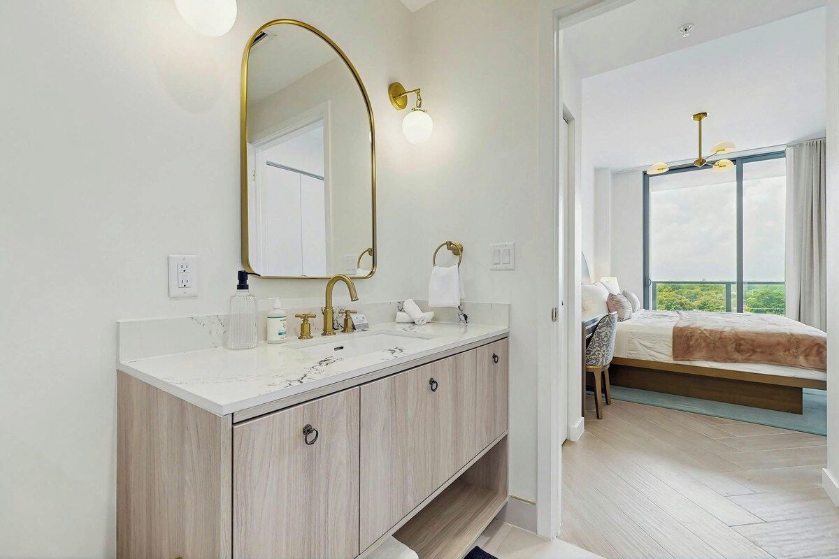 A modern bathroom with a large mirror, dual sinks, and a vanity with storage.