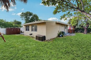 A single-story house with a small front yard, a garage, and a tree. - The Palms Unit 1 - Enclosed Yard (Fort Lauderdale)