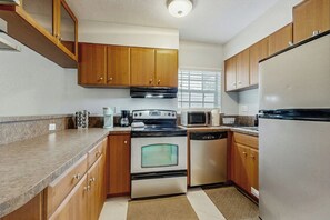 A kitchen with wooden cabinets, a stainless steel refrigerator, a microwave, an oven, and a dishwasher. - The Palms Unit 1 - Enclosed Yard (Fort Lauderdale)