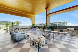 An outdoor patio with seating, tables, and a view of a modern building. - NoMad #415 - Private Balcony (Miami)