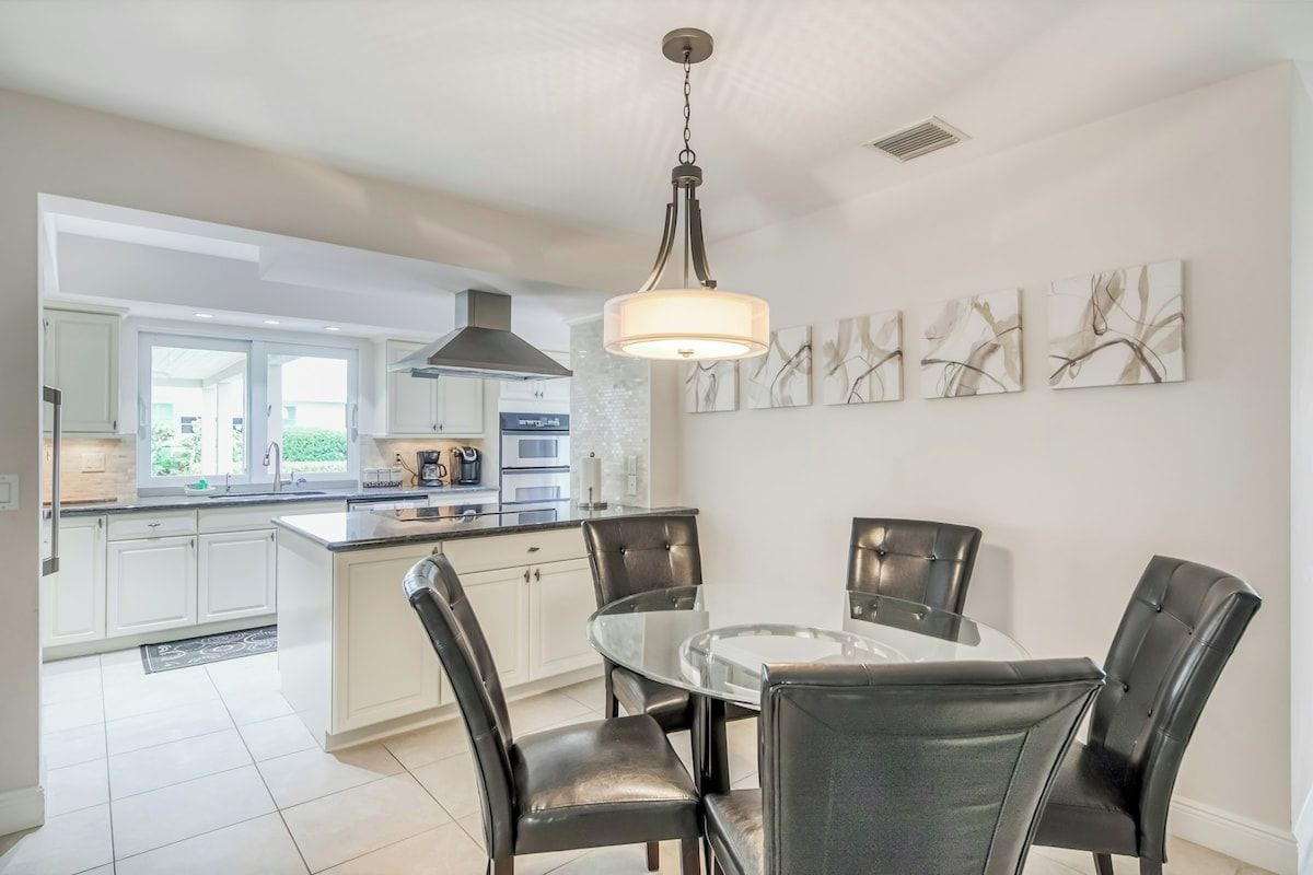 A modern kitchen with a central island, dining table, and chairs.