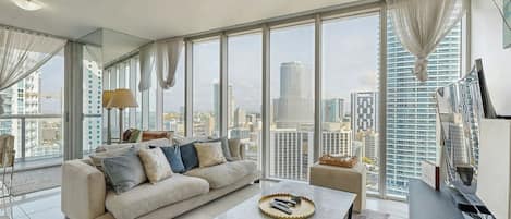 Ein modernes Wohnzimmer mit großem Fenster, einer Couch, einem Couchtisch und Blick auf die Stadt.