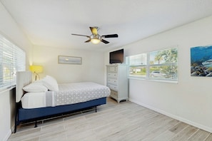 A bedroom with a bed, a ceiling fan, a TV, a dresser, and a window with blinds. - Pompano Beach Getaway (Pompano Beach)