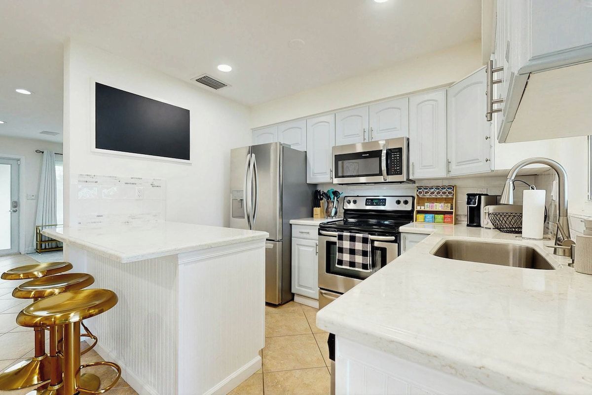 A modern kitchen with white cabinets, stainless steel appliances, and a marble countertop.