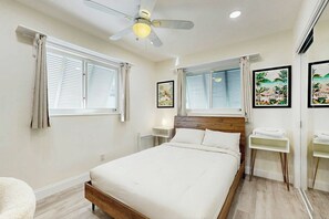 A bedroom with a bed, a ceiling fan, two bedside tables, and artwork on the walls. - Terrace 17 - Private Pool (Fort Lauderdale)