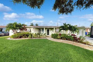 A single-story house with a front lawn, a driveway, and a garage. - Terrace 17 - Private Pool (Fort Lauderdale)