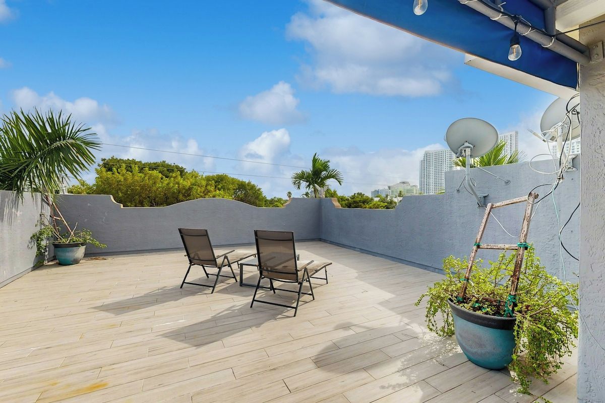 A rooftop terrace with two chairs, a potted plant, and a satellite dish.