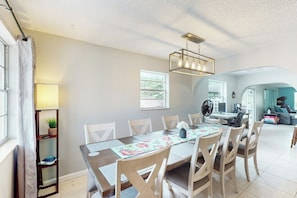 A dining area with a long table, chairs, a ceiling light fixture, and a view into the living room. - Scuba Shack - Enclosed Backyard (West Palm Beach)