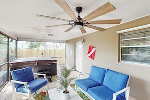 A room with a ceiling fan, a sofa, a chair, a small table with a plant, and a window with blinds. - Scuba Shack - Enclosed Backyard (West Palm Beach)