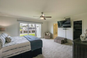 A bedroom with a bed, a ceiling fan, a TV, and a view of the outdoors. - Paradise Manor - Private Pool (Pompano Beach)