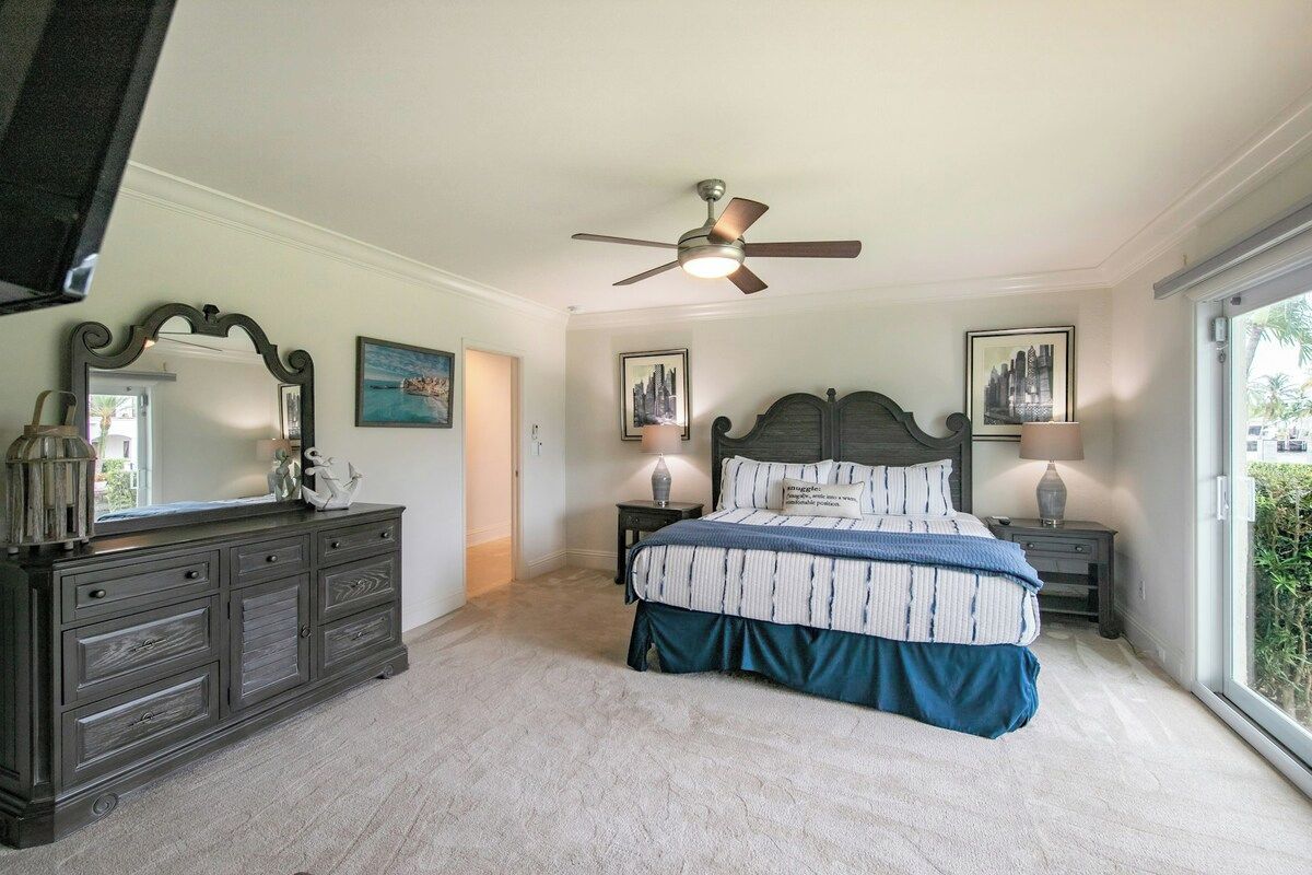 A bedroom with a bed, dresser, nightstands, and a ceiling fan.