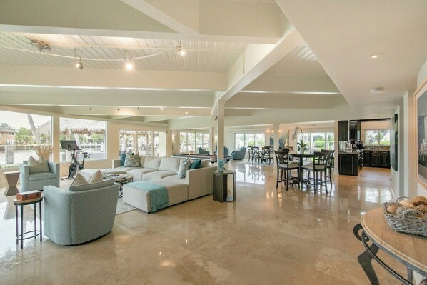 A spacious living area with a large sofa, a dining table, and a kitchen in the background. - Paradise Manor - Private Pool (Pompano Beach)