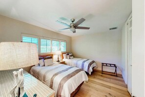 A bedroom with two beds, a ceiling fan, a table with a lamp, and a window with blinds. - Singer Island Serenity (West Palm Beach)