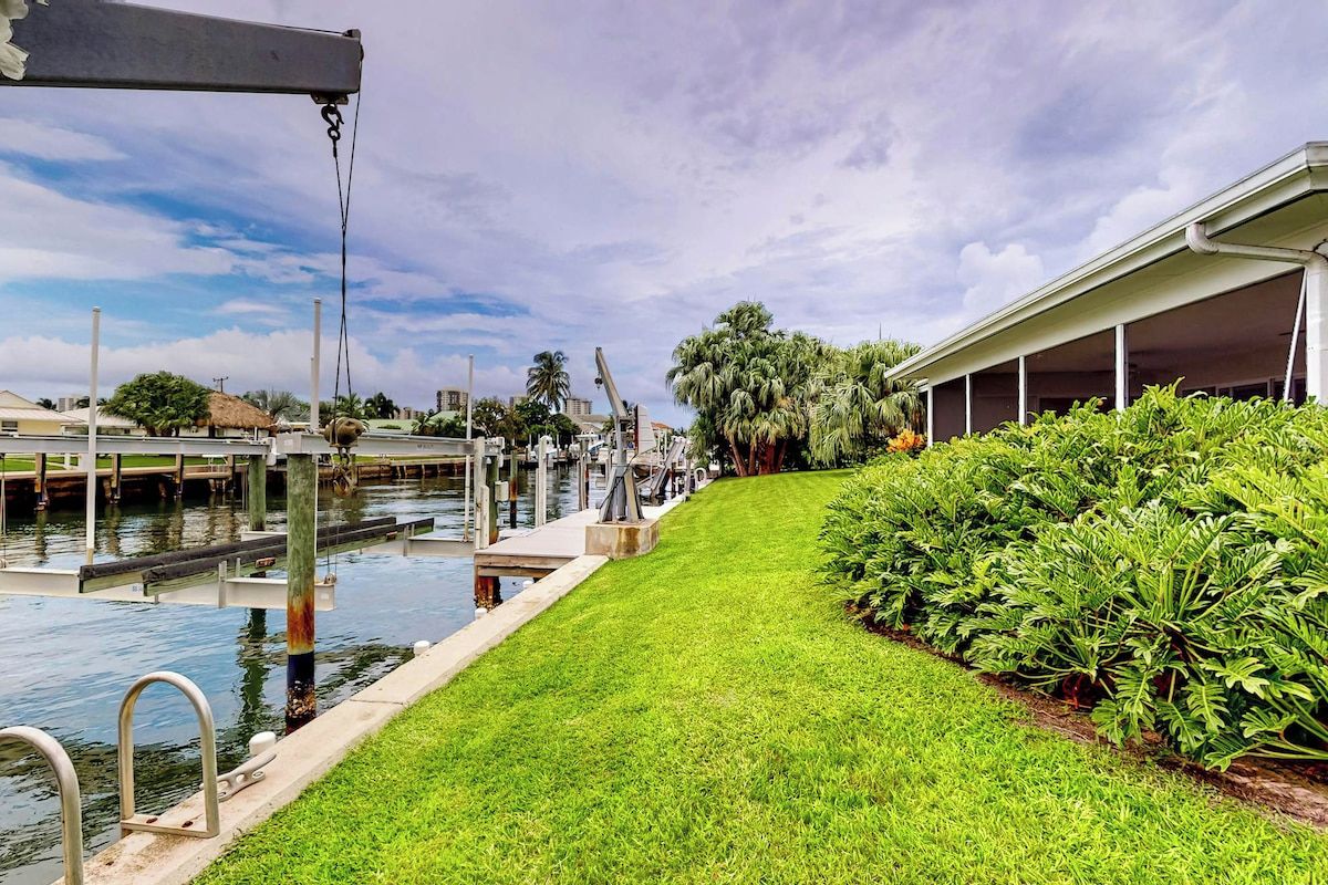 A marina with a grassy pathway, water, and a building with a covered area.