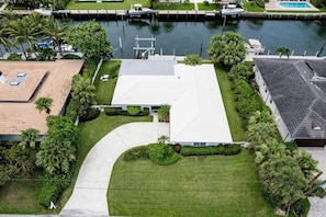 An aerial view of a residential property with a large house, a swimming pool, and a dock with boats. - Singer Island Serenity (West Palm Beach)
