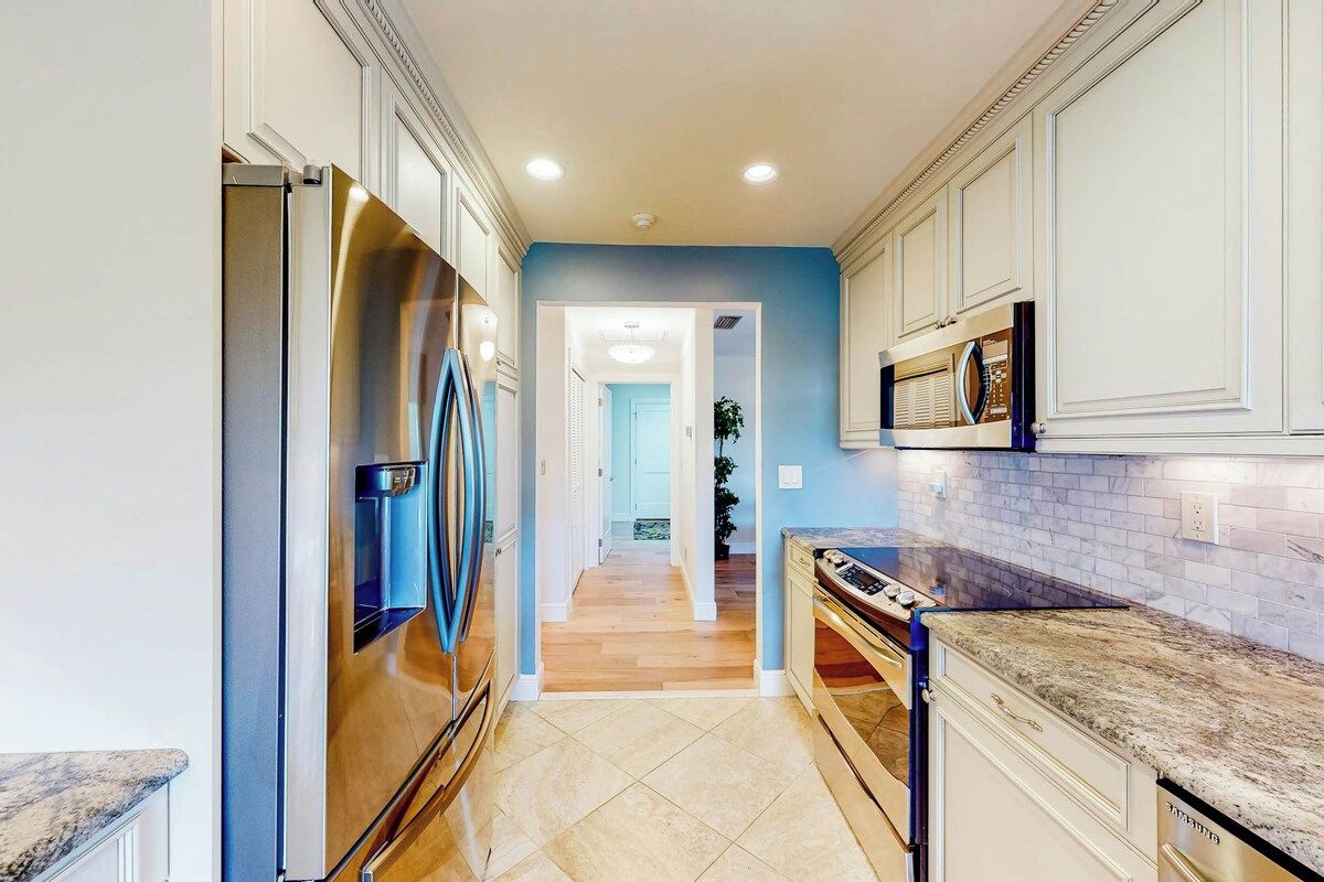 A kitchen with a stainless steel refrigerator, a microwave, and a granite countertop.