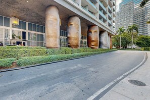 A modern building with large stone pillars, a curved road, and a well-maintained hedge. - Iconic Views - Luxury Condo in the Heart of Brickell (Miami)