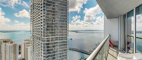A high-rise building with a balcony overlooking a marina and a bridge.