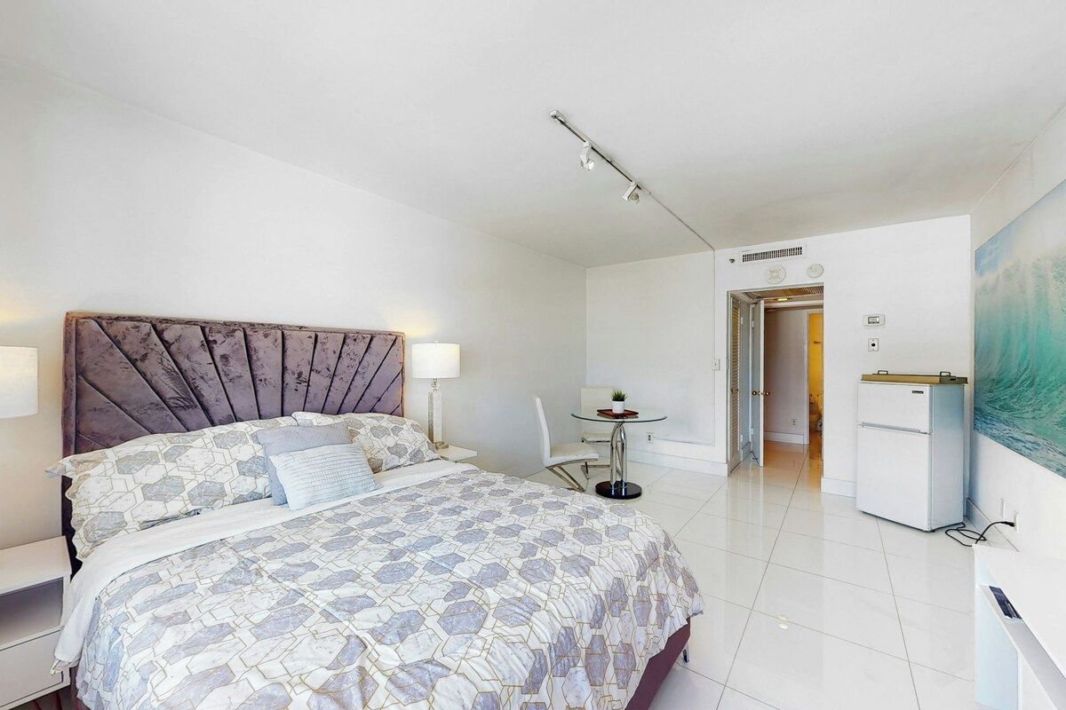 A modern bedroom with a large bed, bedside tables, a desk, and a chair.