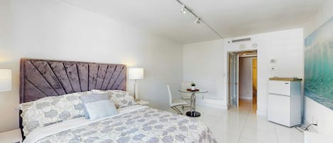 Un dormitorio moderno con una cama grande, mesitas de noche, un escritorio y una silla.