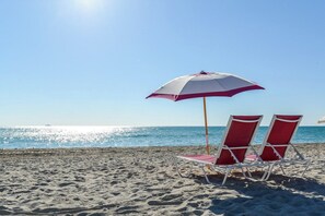 A beach scene with two red and white beach chairs and a matching umbrella. - Decoplage Paradise - Unit A (Miami Beach)