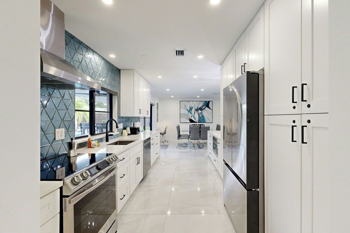 Una cocina moderna con una isla central, electrodomésticos de acero inoxidable y salpicadero de azulejos.