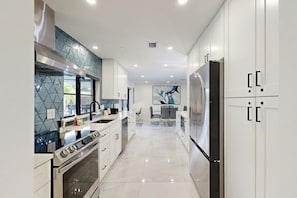 A modern kitchen with a central island, stainless steel appliances, and a tiled backsplash. - The Favorite Place - Private Pool (Fort Lauderdale)