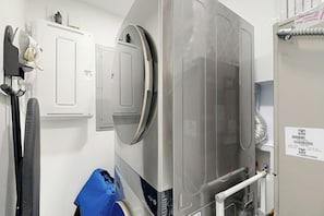A laundry room with a large industrial washing machine, a drying rack, and a blue bucket. - The Favorite Place - Private Pool (Fort Lauderdale)