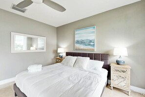 Ein Hotelzimmer mit Bett, Nachttisch, Lampe, Spiegel und einem Gemälde an der Wand.