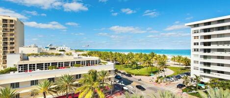 A coastal hotel with multiple floors, a parking area, and a view of the beach.
