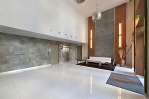 A modern lobby with a reception desk, seating area, and a large mirror reflecting the space. - Modern Ocean Drive Condo in the Heart of Sobe (Miami Beach)