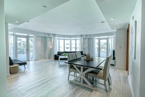 A spacious living area with a dining table, sofa, and large windows. - Modern Ocean Drive Condo in the Heart of Sobe (Miami Beach)
