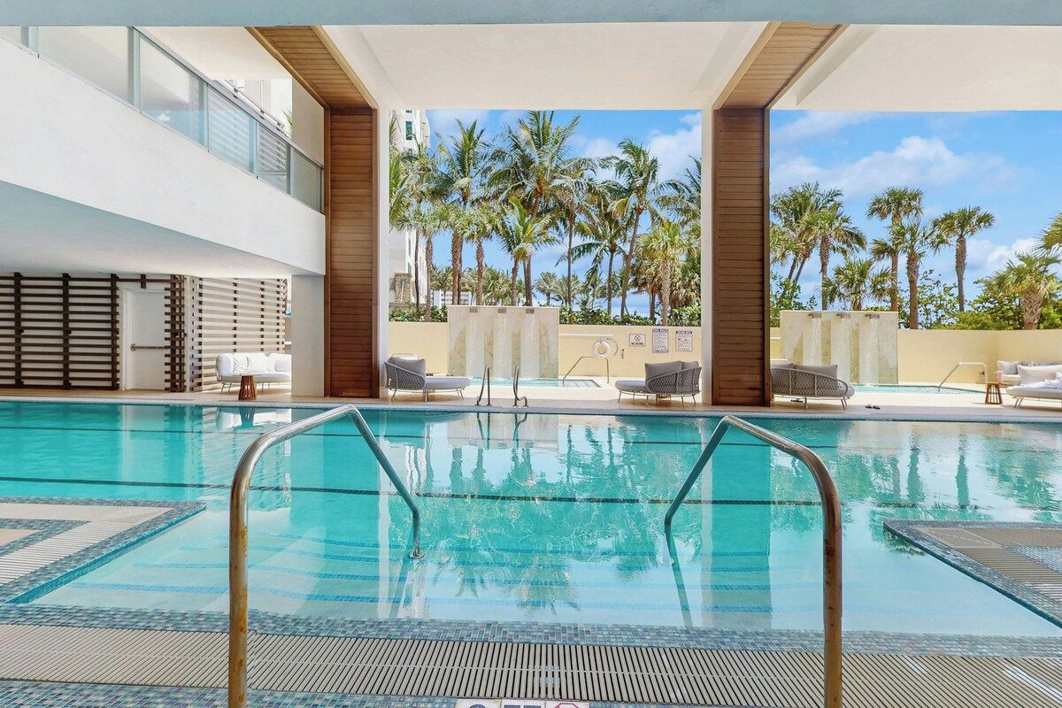 Une piscine avec vue sur les palmiers et un ciel dégagé.
