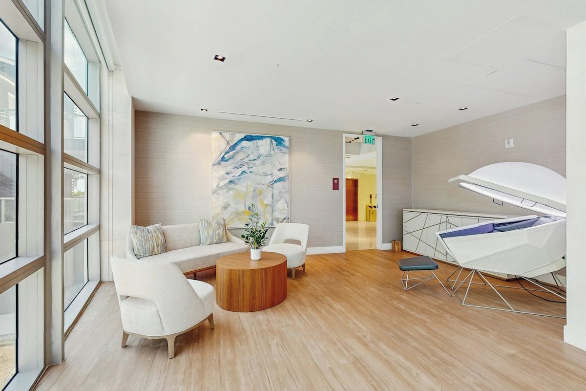 Een moderne hotellobby met een zithoek, een salontafel en een groot abstract schilderij aan de muur.