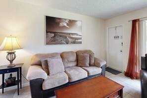 Ein Wohnzimmer mit Sofa, Couchtisch, Lampe und einem Gemälde an der Wand.