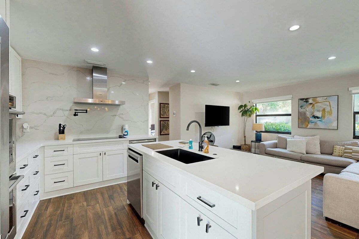 A modern kitchen with white cabinetry, a central island, and a built-in stove.