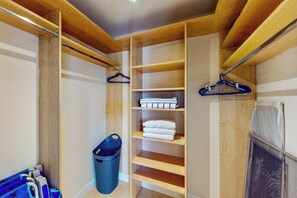 Ein begehbarer Kleiderschrank mit Holzregalen, einer Kleiderstange und einem Wäschekorb.