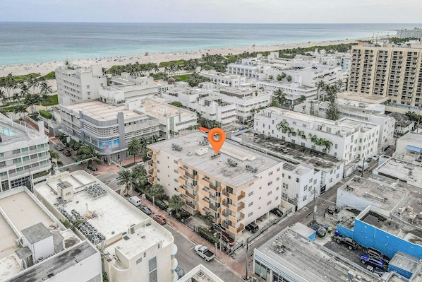 Ein Stadtgebiet mit einem markanten, orangefarbenen Wahrzeichen, umgeben von mehrstöckigen Gebäuden, einem Strand und freiem Blick auf den Ozean.